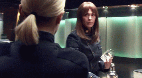 Two Women Standing One Holding Bottle GIF