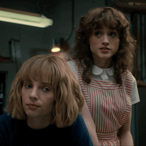 Two Women Are Standing Next To Each Other And One Is Wearing A Striped Dress GIF