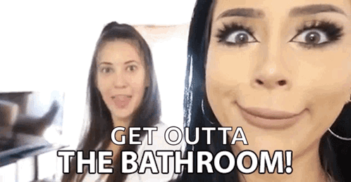 two women are standing next to each other and one of them is making a funny face and saying `` get outta the bathroom !