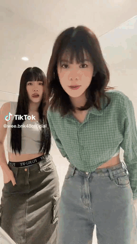 Two Women Are Standing Next To Each Other And One Of Them Is Wearing A Crop Top . GIF