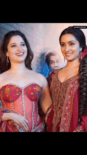 Two Women Are Standing Next To Each Other And Smiling . One Of The Women Is Wearing A Corset . GIF