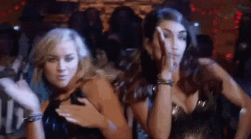 Two Women Are Standing Next To Each Other In A Club And Dancing . GIF