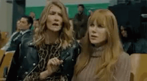 Two Women Are Standing Next To Each Other In A Crowd Of People In A Theater . GIF