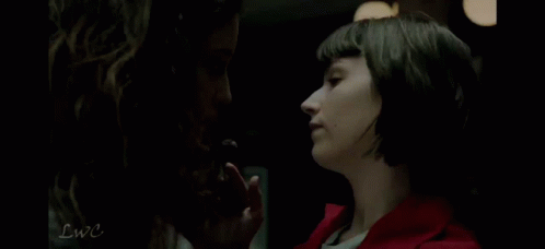 Two Women Are Standing Next To Each Other In A Dark Room . GIF