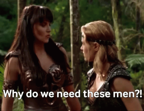 Two Women Are Standing Next To Each Other In A Forest And Talking To Each Other . GIF