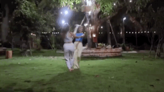 Two Women Are Standing Next To Each Other In A Park At Night . GIF