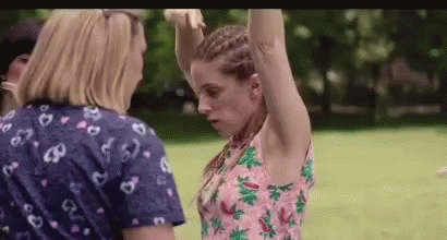 Two Women Are Standing Next To Each Other In A Park With Their Arms Up . GIF