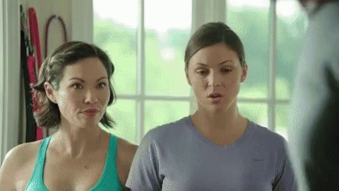 Two Women Are Standing Next To Each Other In A Room And Looking At Each Other . GIF