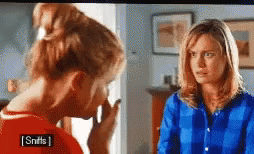 Two Women Are Standing Next To Each Other In A Room And One Of Them Is Wearing A Blue Shirt That Says Sniffs . GIF
