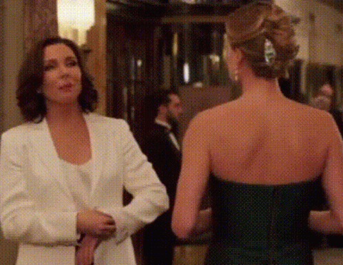 Two Women Are Standing Next To Each Other In A Room Talking To Each Other . GIF