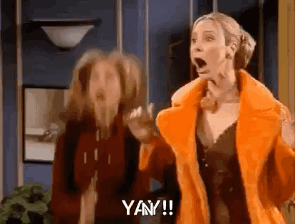 Two Women Are Standing Next To Each Other In A Room With Their Mouths Open And One Of Them Is Wearing An Orange Fur Coat GIF