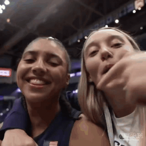 Two Women Are Standing Next To Each Other In A Stadium And Smiling At The Camera . GIF
