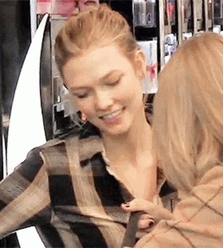 Two Women Are Standing Next To Each Other In A Store And One Of Them Is Holding The Other 'S Arm . GIF