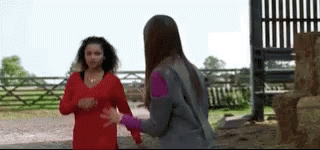 Two Women Are Standing Next To Each Other In Front Of A Fence . GIF