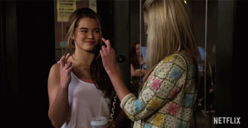 Two Women Standing Next To Netflix Sign GIF