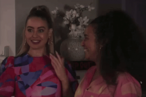 Two Women Are Standing Next To Each Other In Front Of A Sign That Says ' The Quiet ' GIF
