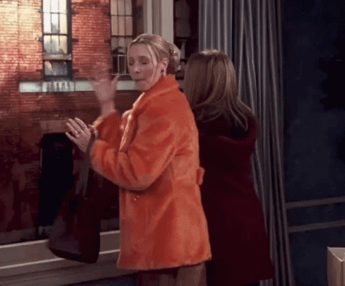 Two Women Are Standing Next To Each Other In Front Of A Window . GIF