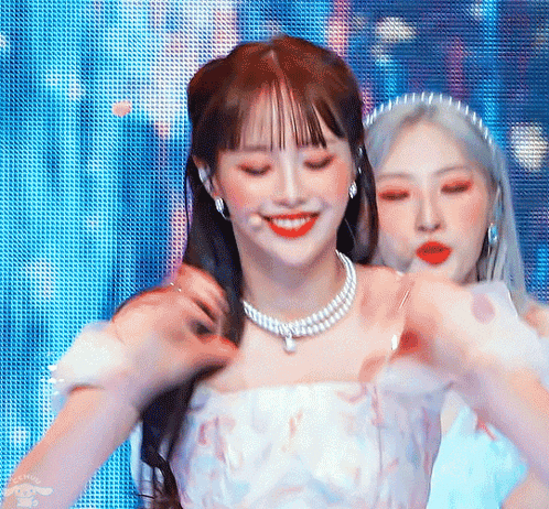 Two Women Are Standing Next To Each Other On A Stage . One Of The Women Is Wearing A Pearl Necklace . GIF