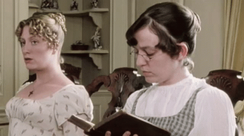 Two Women Are Standing Next To Each Other One Reading A Book GIF