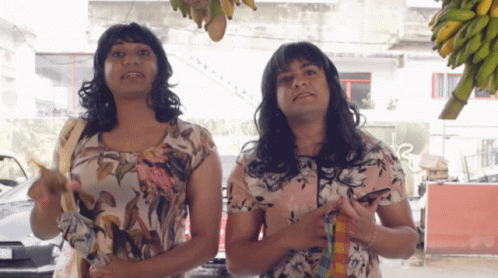 Two Women Are Standing Next To Each Other With One Pointing At The Camera GIF