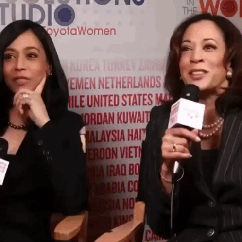 Two Women Are Talking Into Microphones In Front Of A Wall That Says " In The Wo " GIF