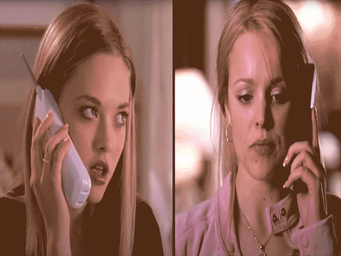 Two Women Are Talking On Their Cell Phones And One Has A Ring On Her Finger GIF