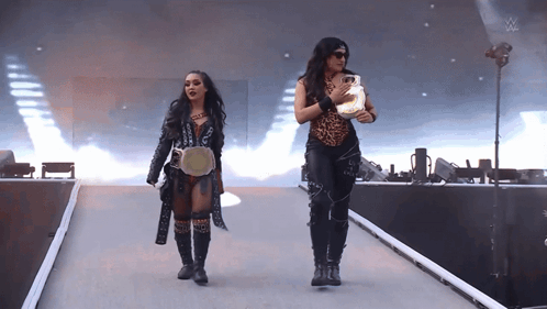 Two Women Are Walking Down A Ramp With A W Logo On The Bottom GIF