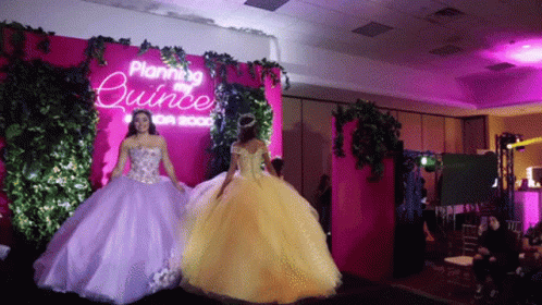 Two Women Are Walking Down A Runway In Front Of A Sign That Says Planning Quince GIF
