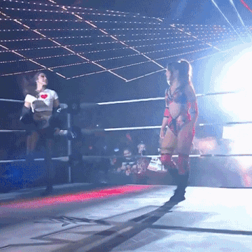 two women are wrestling in a ring and one has a heart on her t-shirt