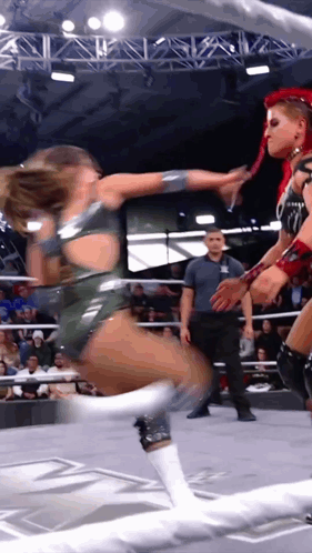two women are wrestling in a ring while a referee watches