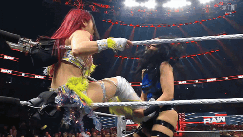 Two Women Are Wrestling In A Ring With The Word Raw On The Walls GIF