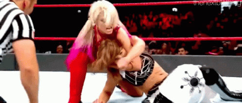 Two Women Are Wrestling In A Wrestling Ring With A Referee Watching . GIF