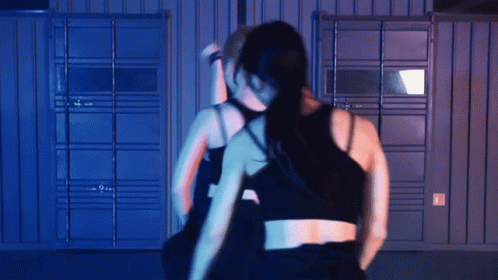 Two Women Dancing in Dark Room with Blue Wall