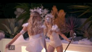 Two Women Dressed As Snowflakes Are Dancing Together In A Dark Room . GIF