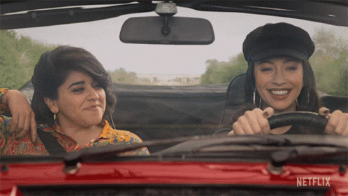 Two Women Driving Red Car With Netflix On Windshield GIF