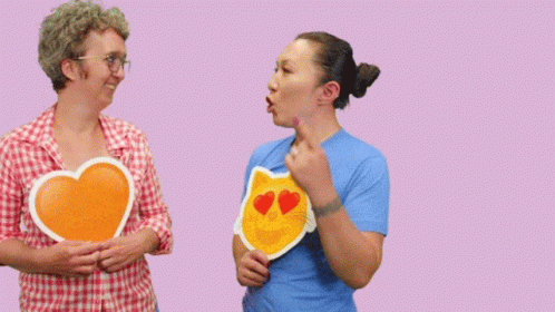 Two Women Holding Signs That Say No You 'Re Awesome On A Pink Background GIF
