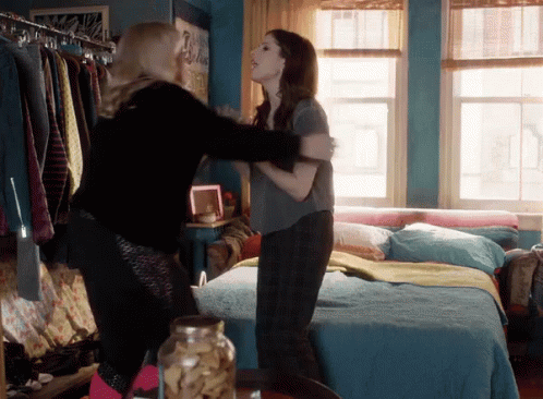 Two Women Hugging In A Bedroom With A Jar Of Cookies In The Foreground GIF