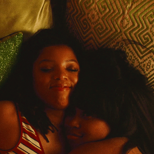 Two Women Hugging On Bed With Patterned Pillow GIF