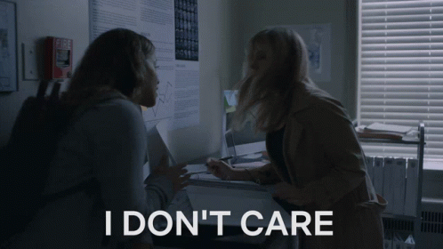 Two Women In A Dark Room With The Words I Don 'T Care On The Bottom Right GIF