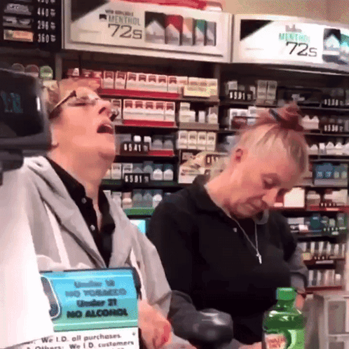 Two Women In A Store With A Sign That Says No Alcohol On It GIF