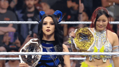 Two Women In A Wrestling Ring Holding Trophies With The Letters W In The Background GIF