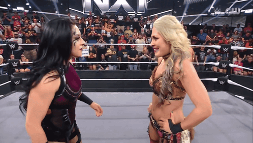 Two Women In A Wrestling Ring With The Word Nxt On The Wall GIF