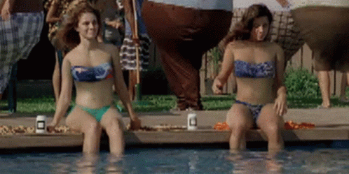 Two Women In Bikinis Are Sitting In A Swimming Pool GIF