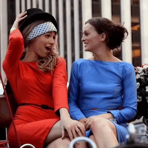 Two Women in Blue and Red Dresses Laughing