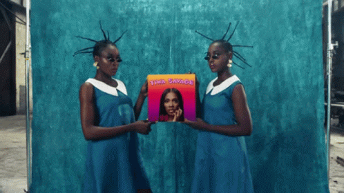 Two Women In Blue Dresses Holding A Cd Titled ' Awa Savage ' GIF