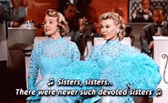 Two Women In Blue Dresses Singing Sisters