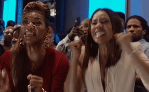 Two Women In Crowd Arms Up Making Funny Faces GIF