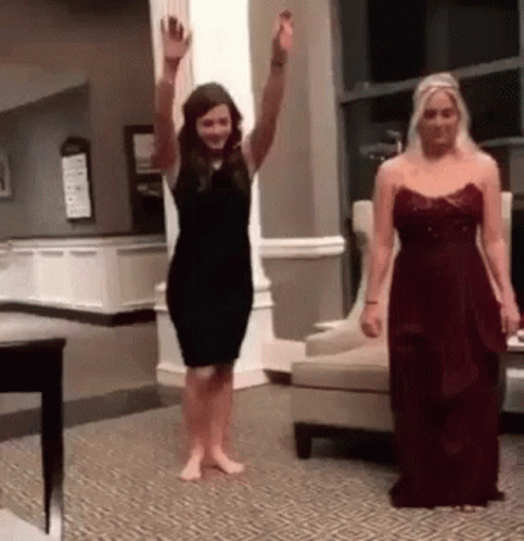Two Women In Dresses Are Dancing In A Living Room . GIF