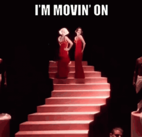 Two Women In Red Dresses Are Standing Next To Each Other On Stairs . GIF