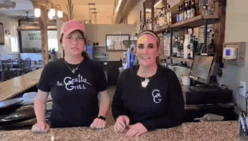 Two Women in The Grotto Grill Shirts Behind Counter